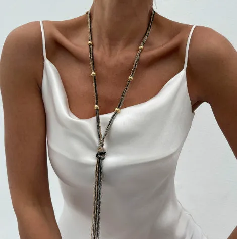 Simple Y-shaped metal tassel necklace set with gold finish and matching earrings on white background