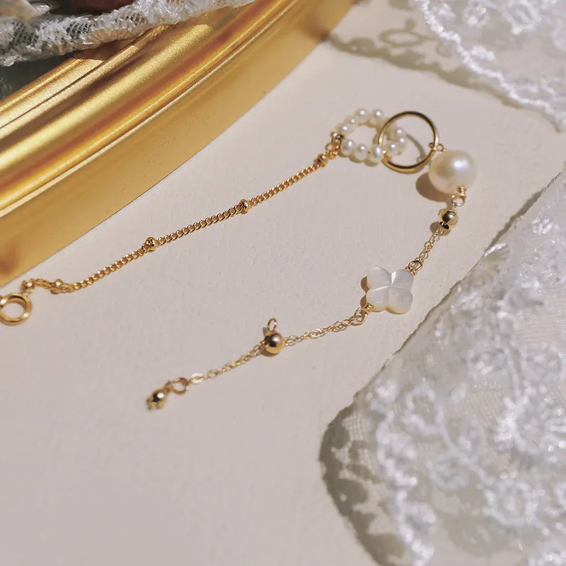 Women's natural freshwater pearl bracelet with gold-plated clasp and floral charm accents on a white background.