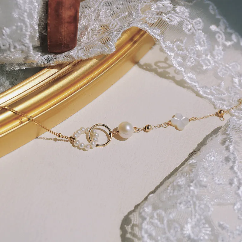 Women's natural freshwater pearl bracelet with gold-plated clasp and floral charm accents on a white background.