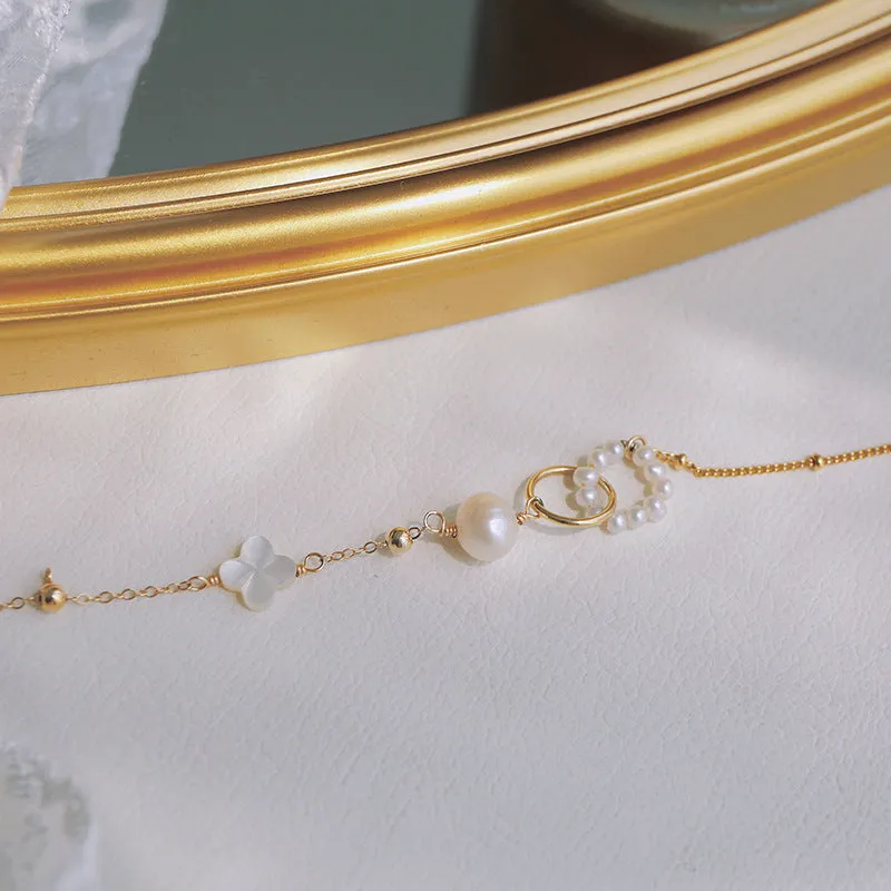 Women's natural freshwater pearl bracelet with gold-plated clasp and floral charm accents on a white background.