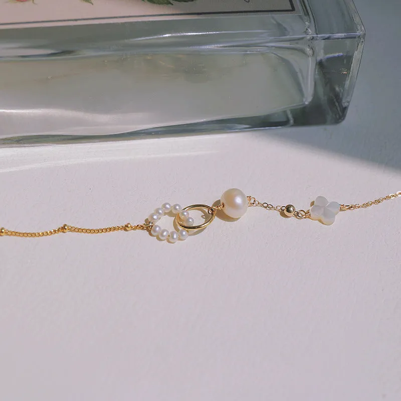 Women's natural freshwater pearl bracelet with gold-plated clasp and floral charm accents on a white background.