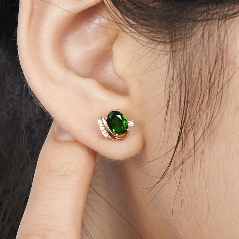Pair of green ghost crystal stud earrings in silver with diamond-cut geometric shape on white background