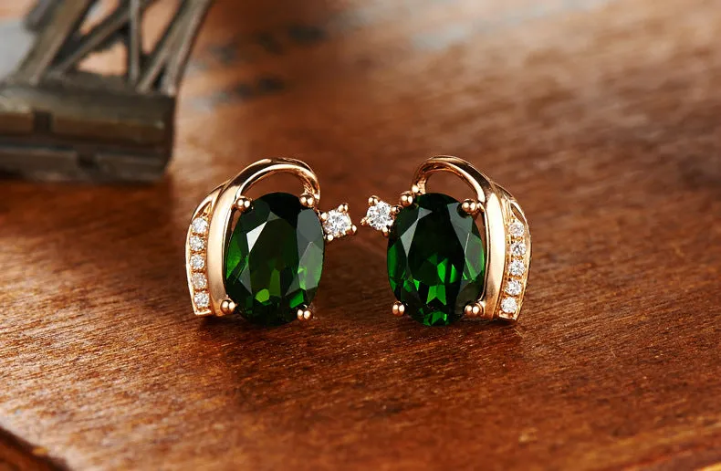 Pair of green ghost crystal stud earrings in silver with diamond-cut geometric shape on white background