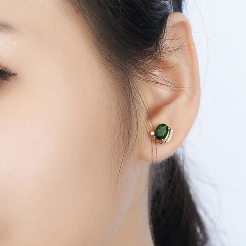 Pair of green ghost crystal stud earrings in silver with diamond-cut geometric shape on white background