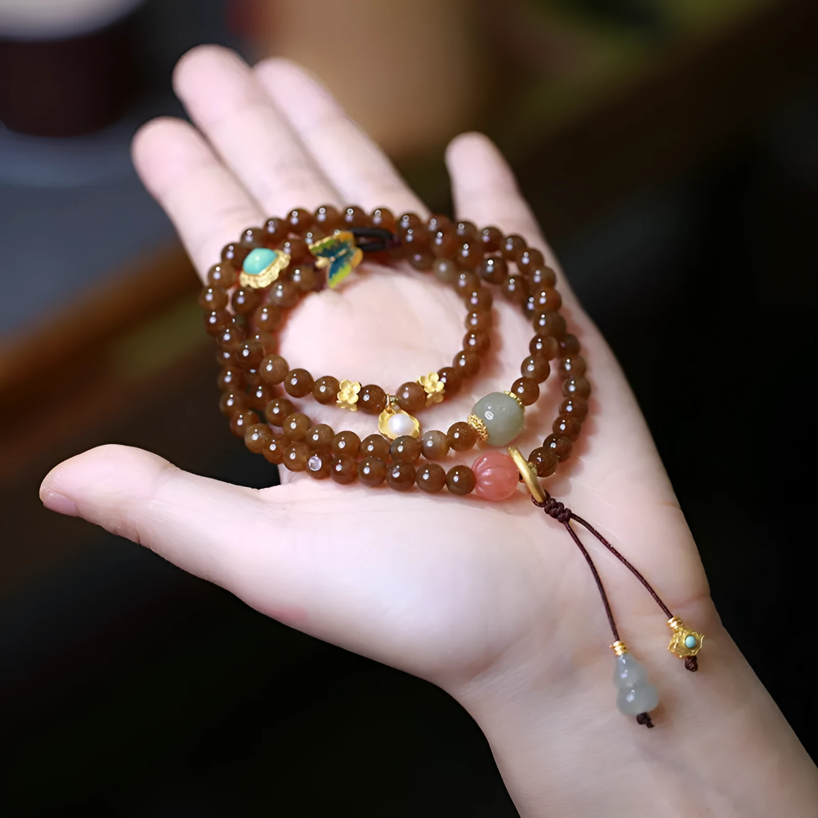 Brown Hetian Jade three-ring bracelet with butterfly and gourd charms on a wrist.