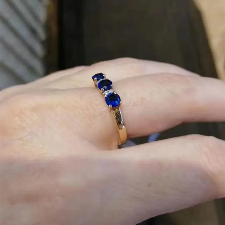 Women's geometric copper electroplated ring with adjustable opening and inlaid blue stone on a neutral background