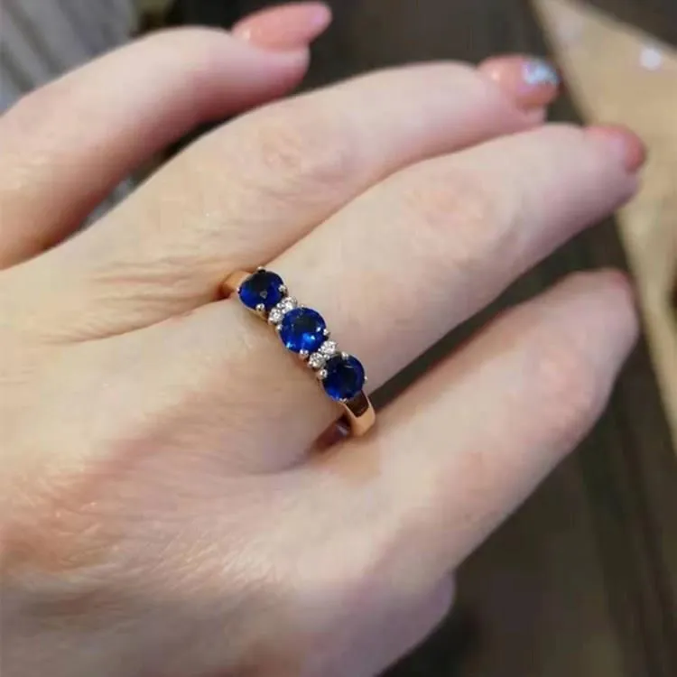 Women's geometric copper electroplated ring with adjustable opening and inlaid blue stone on a neutral background