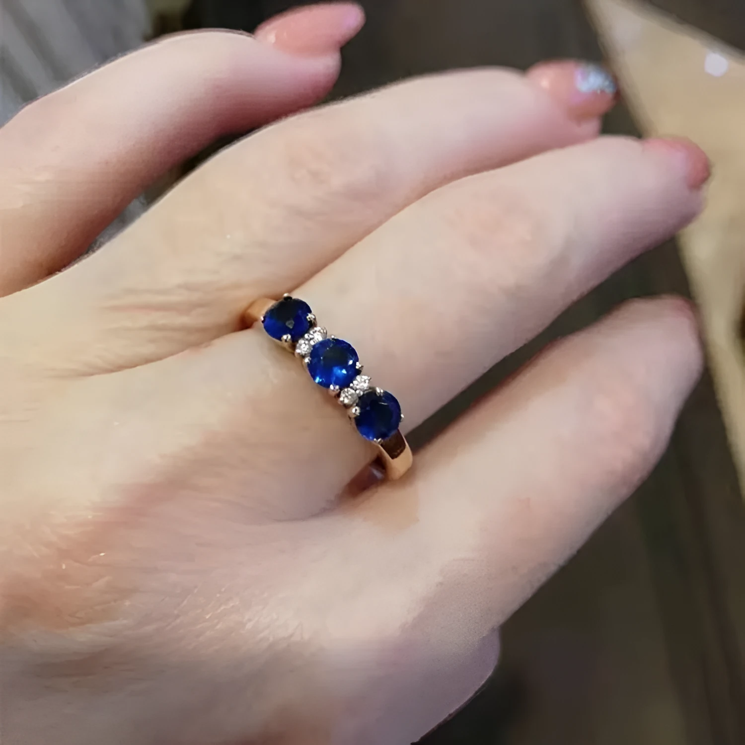 Women's geometric copper electroplated ring with adjustable opening and inlaid blue stone on a neutral background