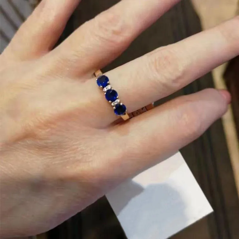 Women's geometric copper electroplated ring with adjustable opening and inlaid blue stone on a neutral background