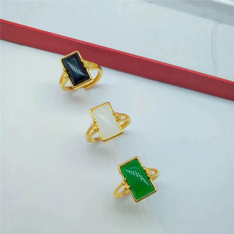 Adjustable gold-plated brass ring with a black artificial gemstone on a neutral background.