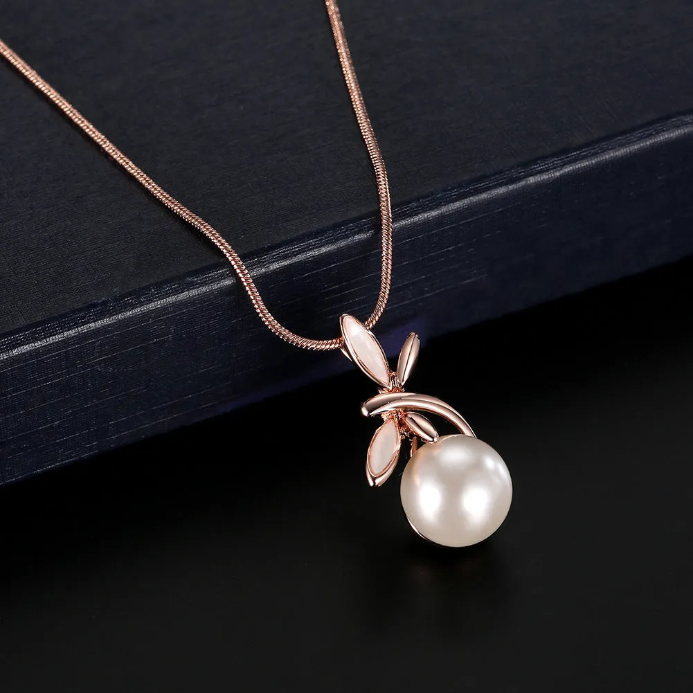 Rose gold alloy necklace with artificial gem pendant and matching earrings on a display surface