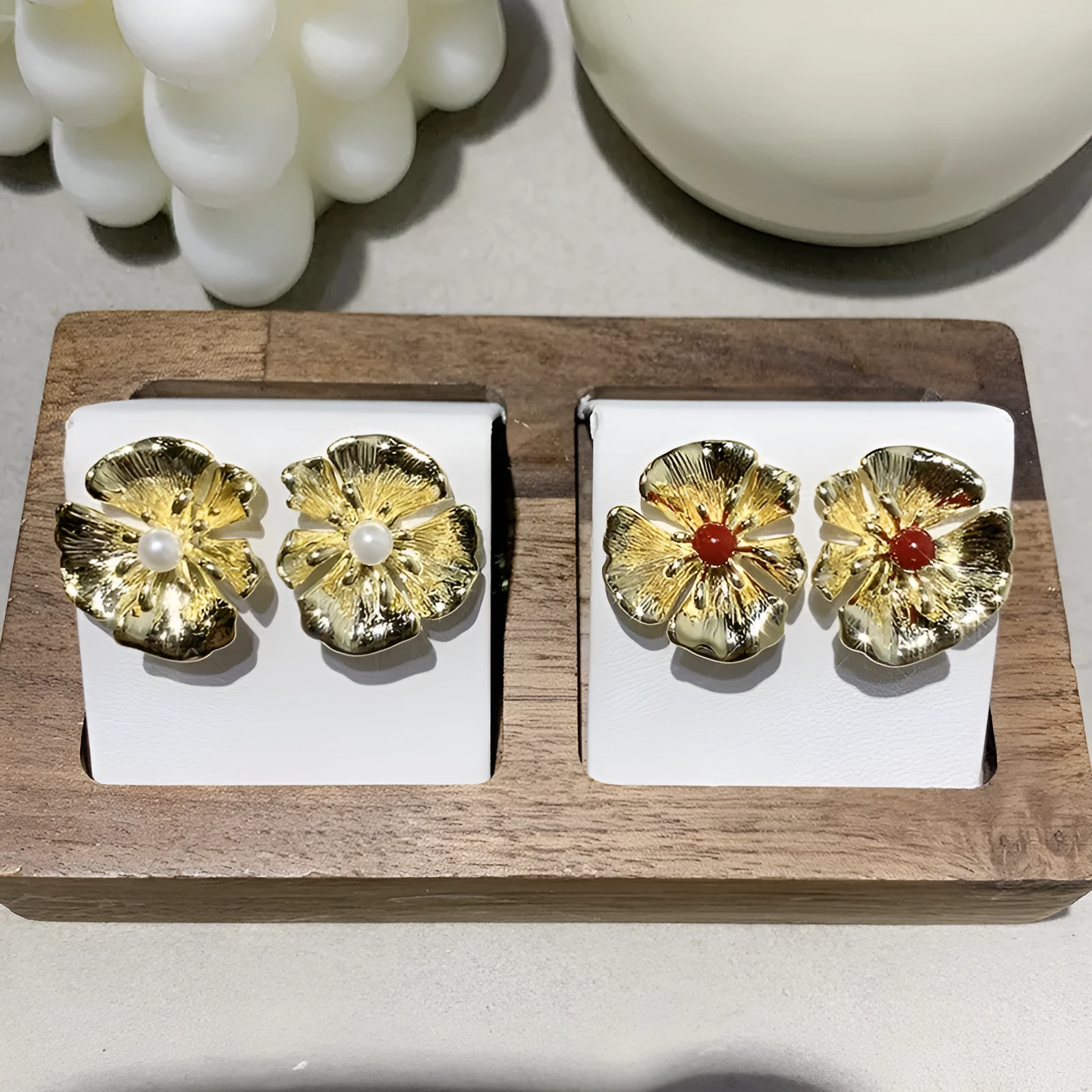 Pearl flower shaped metal earrings in red and white colour options on a grey background