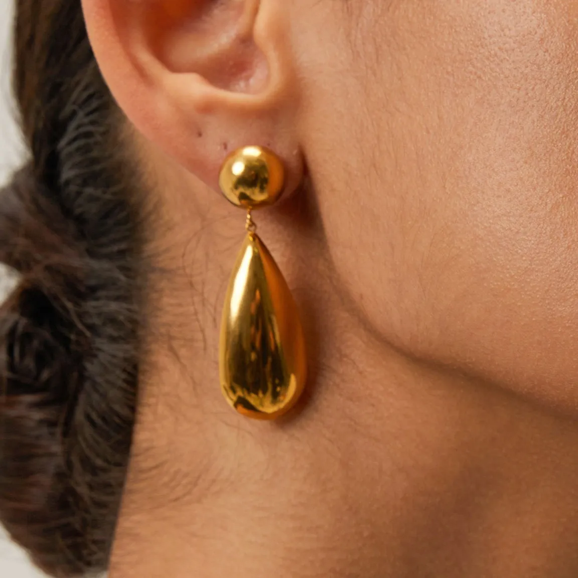 Gold coloured stainless steel earrings with a geometric hemisphere and water drop pendant design.