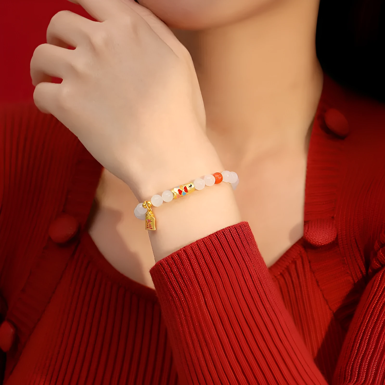 Close-up of a sterling silver bracelet with a blue and orange cold enamel koi fish charm set with Hetian jade.