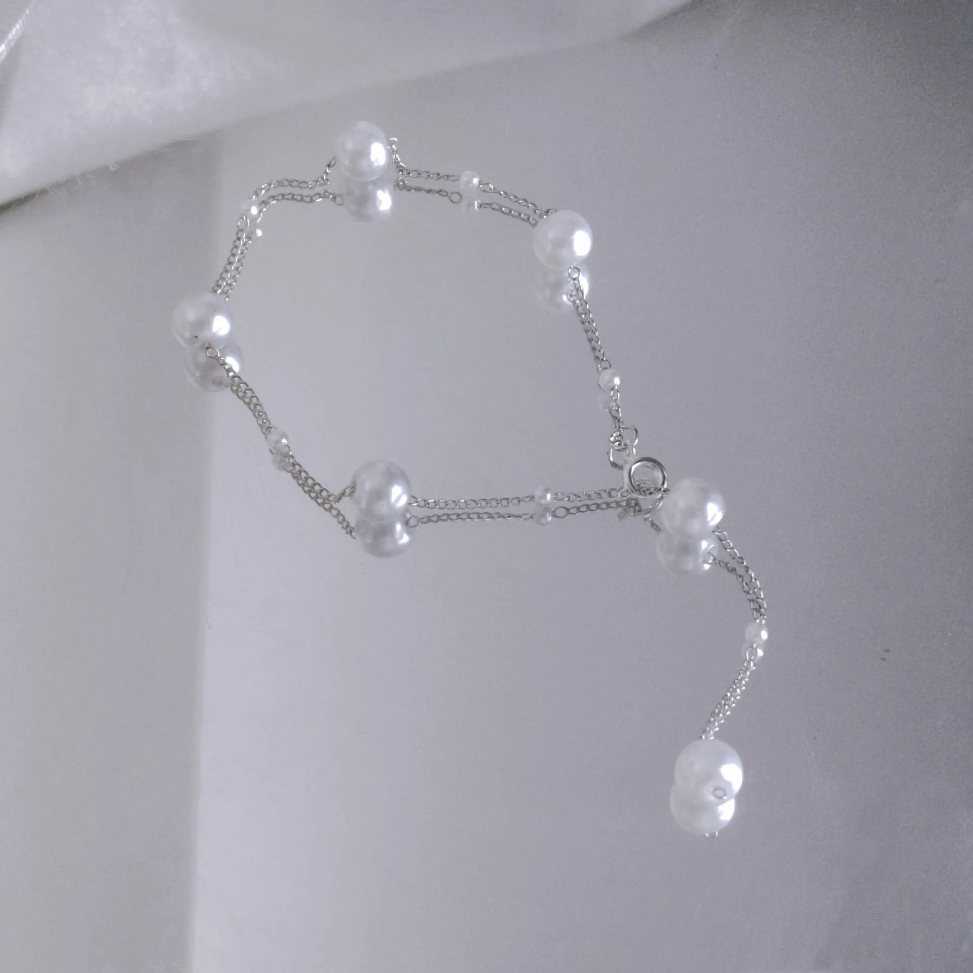 Gold starry pearl choker necklace on a white surface showing imitation pearl chain