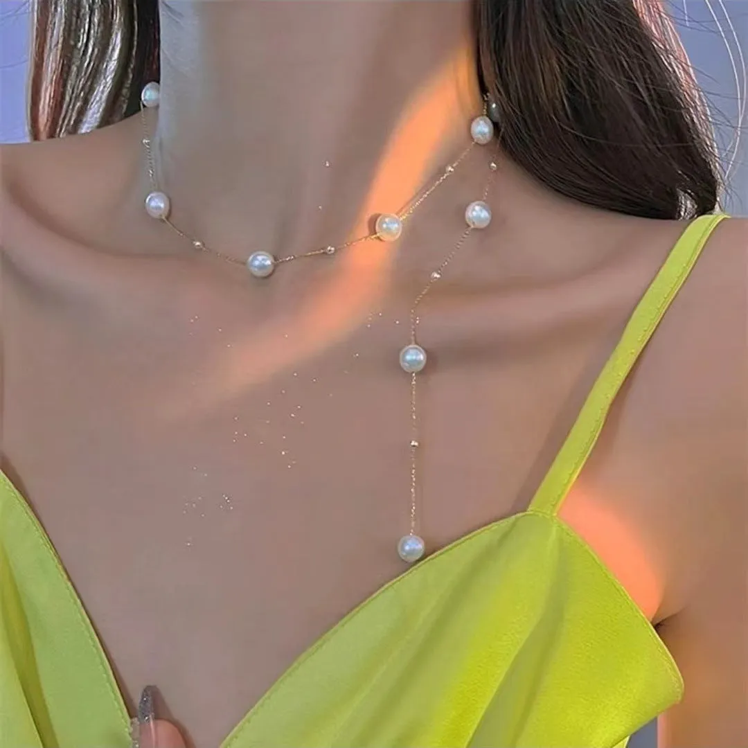 Gold starry pearl choker necklace on a white surface showing imitation pearl chain