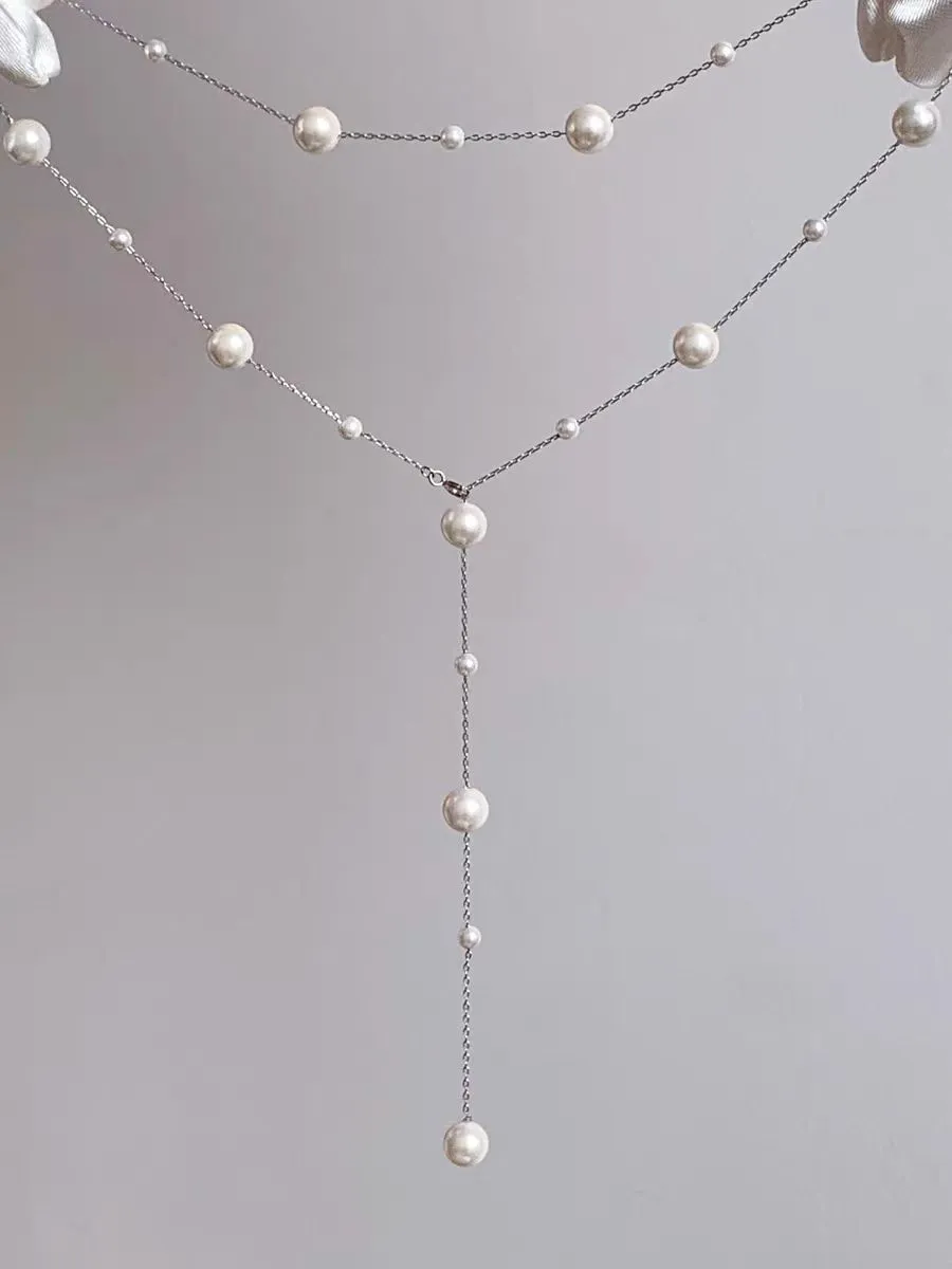 Gold starry pearl choker necklace on a white surface showing imitation pearl chain
