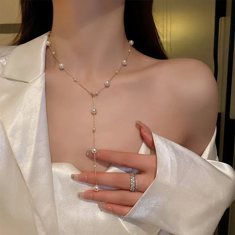 Gold starry pearl choker necklace on a white surface showing imitation pearl chain