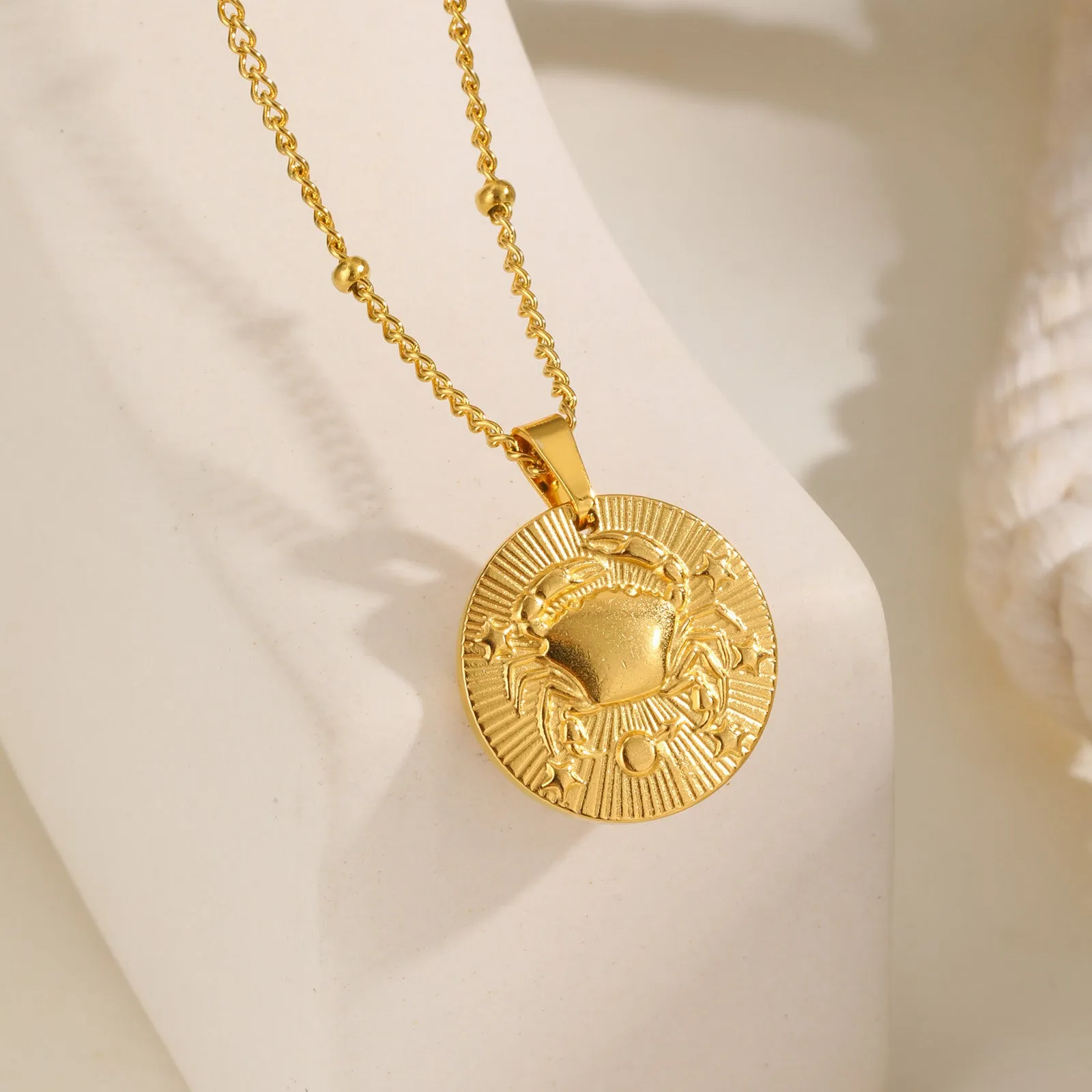 Stainless steel bead necklace with a round pendant embossed with a zodiac constellation, on a cross chain.