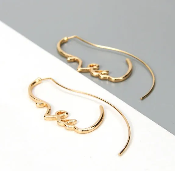 Creative abstract face contour earrings in metal gold finish on a white background