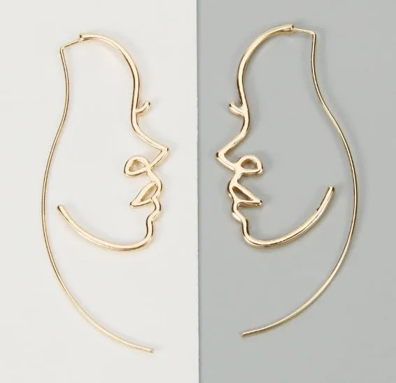 Creative abstract face contour earrings in metal gold finish on a white background
