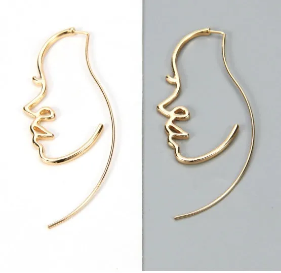Creative abstract face contour earrings in metal gold finish on a white background