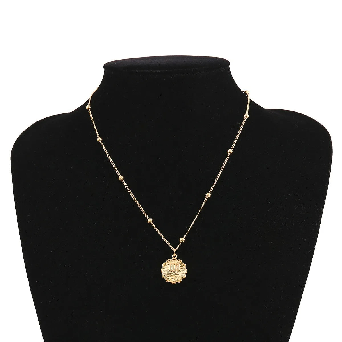 Gold plated metal zodiac constellation pendant necklace with bead chain on white background