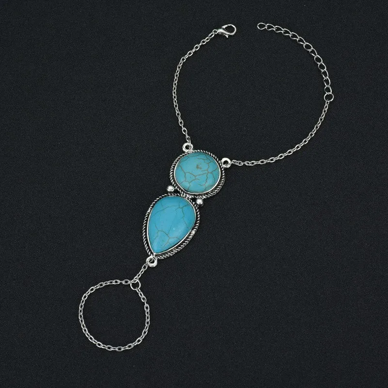 Silver alloy plated drop shape bracelet with turquoise tassel on a neutral background