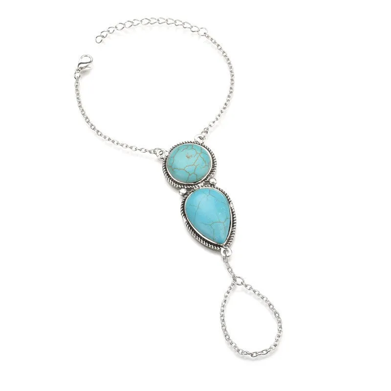 Silver alloy plated drop shape bracelet with turquoise tassel on a neutral background