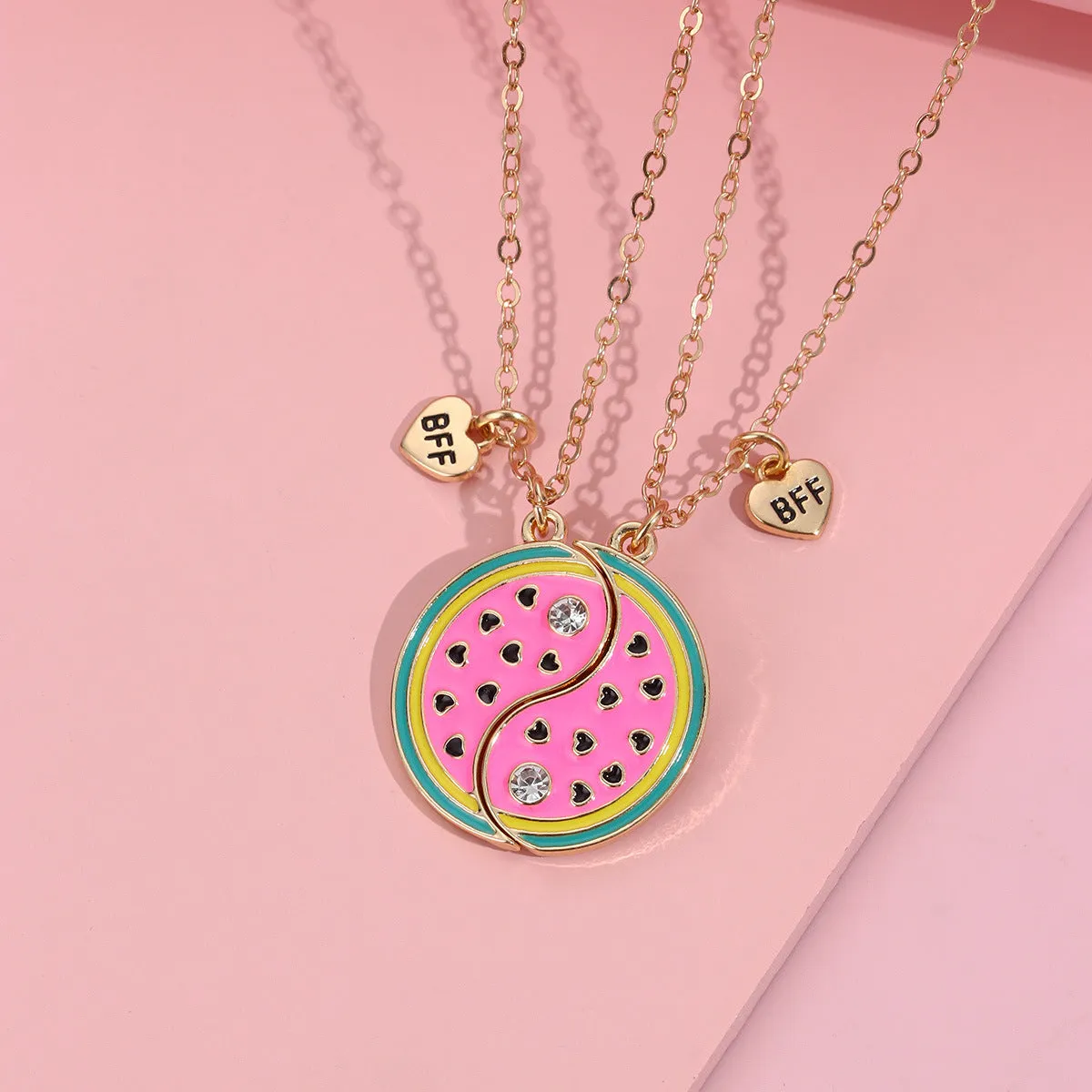 Two matching zinc alloy pendants in donut and watermelon shapes with glossy oil drip finish on cross chains