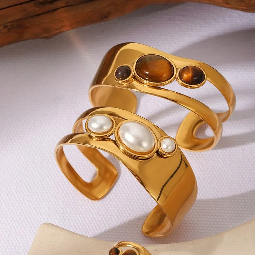 Stainless steel wide face bracelet inlaid with natural tiger eye stone on a neutral background