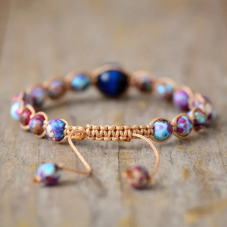 Hand woven friendship bracelet with adjustable cord and single Emperor Stone bead on a plain background.