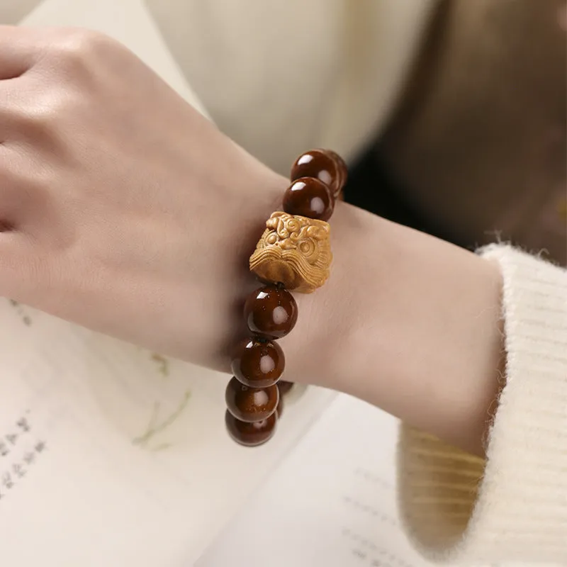 Hand-woven bracelet with 13mm round beads and a carved lion bead centrepiece in ivory nut style.