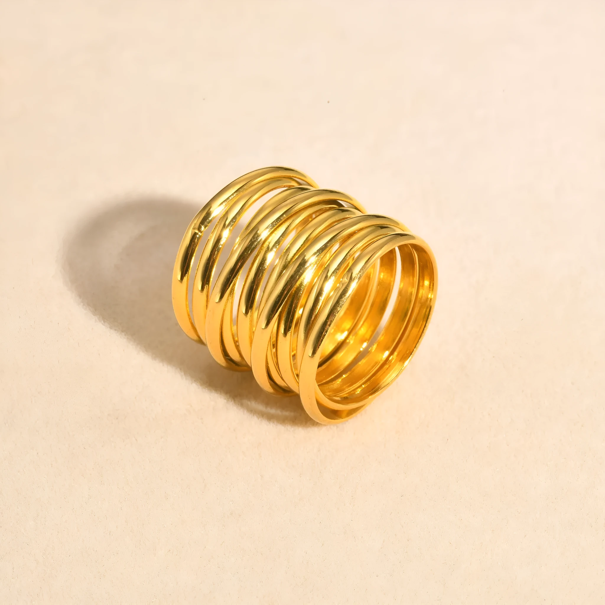 Gold stainless steel multi-loop multi-layer ring on a plain background