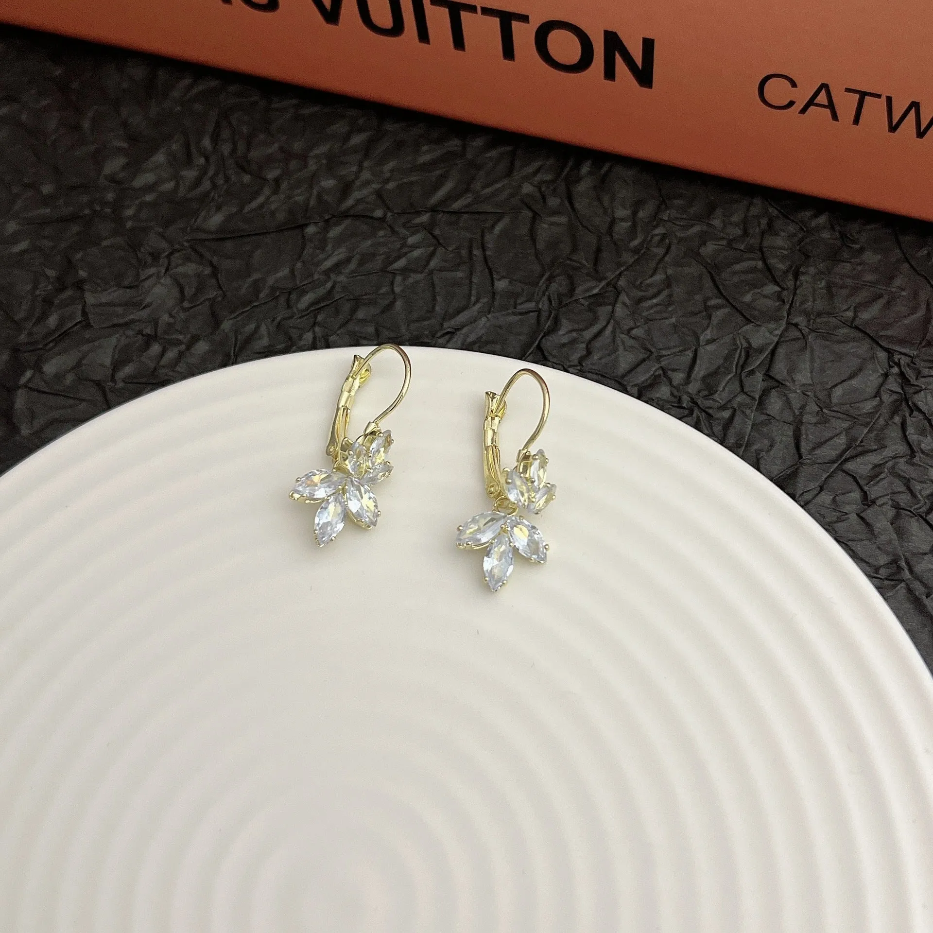 Women's platinum colour leaf earrings with inlaid zircon detailing on alloy background