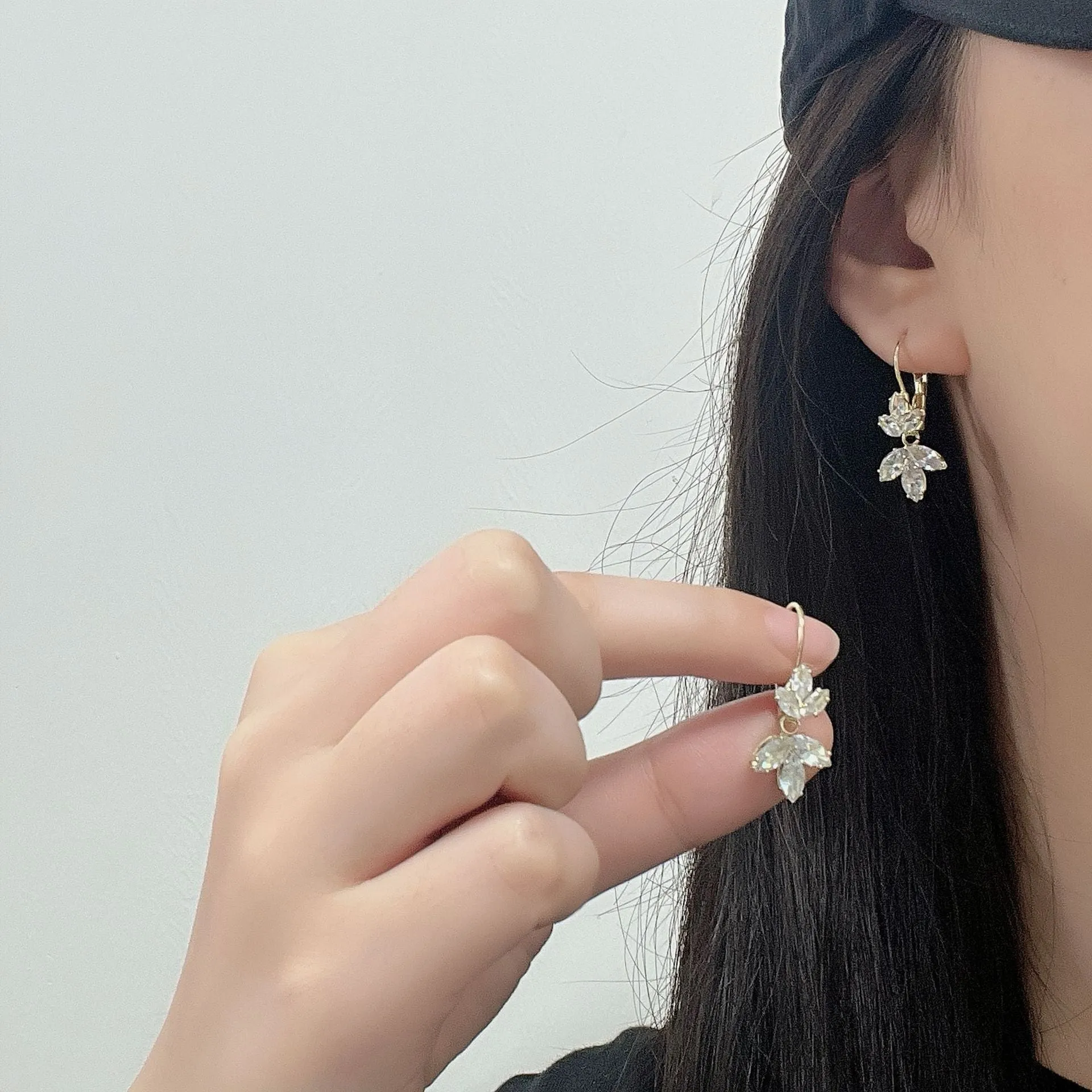Women's platinum colour leaf earrings with inlaid zircon detailing on alloy background