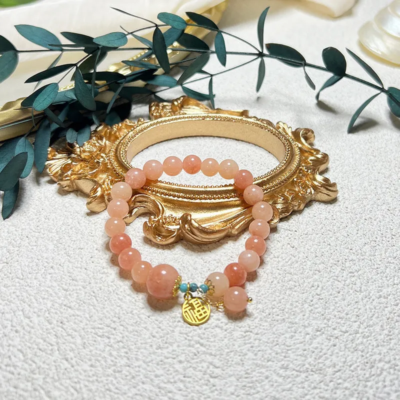 A simple pink natural stone and alloy bracelet with an adjustable clasp on a wrist.