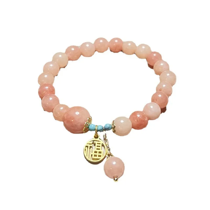 A simple pink natural stone and alloy bracelet with an adjustable clasp on a wrist.