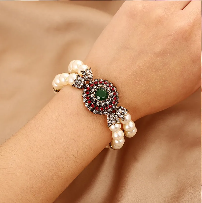 Luxury pearl bracelet in green and red alloy metal on display