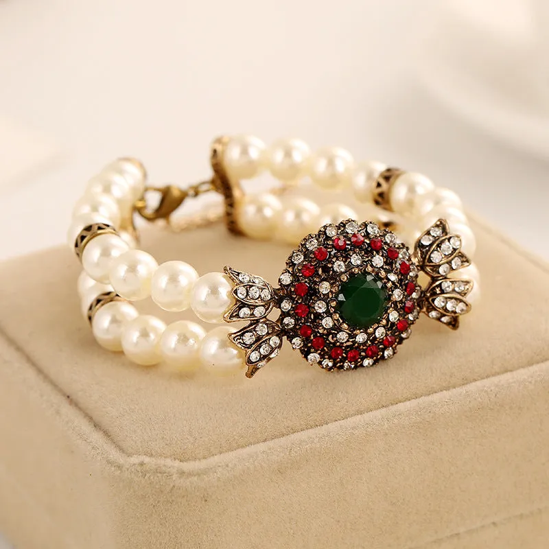 Luxury pearl bracelet in green and red alloy metal on display