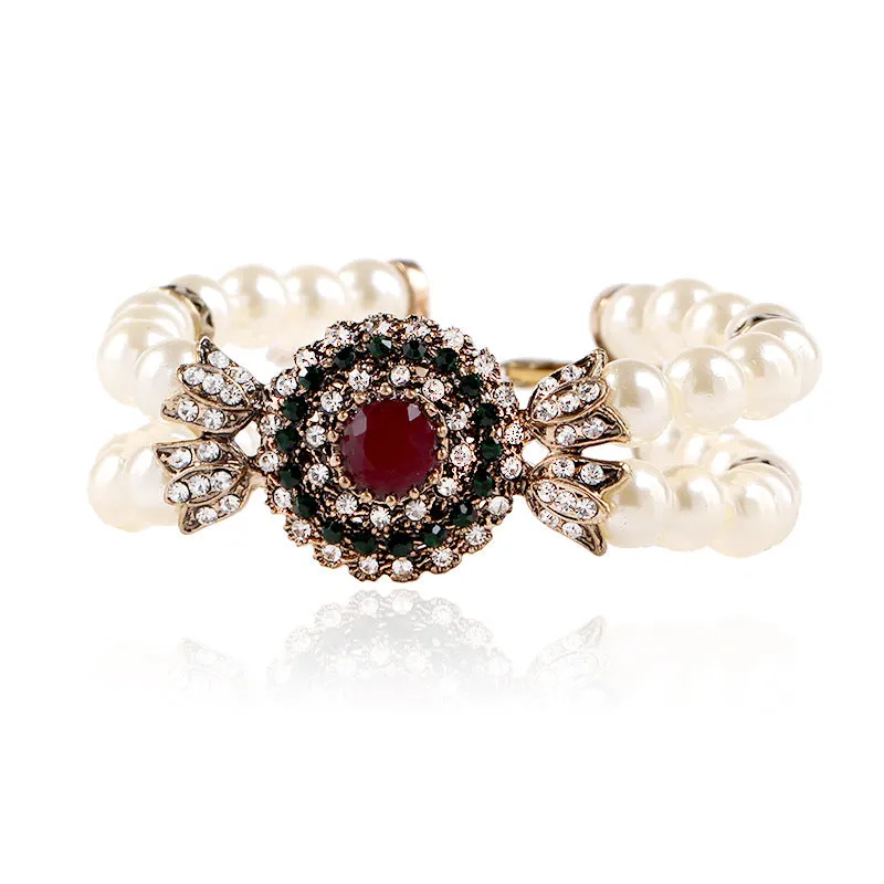 Luxury pearl bracelet in green and red alloy metal on display