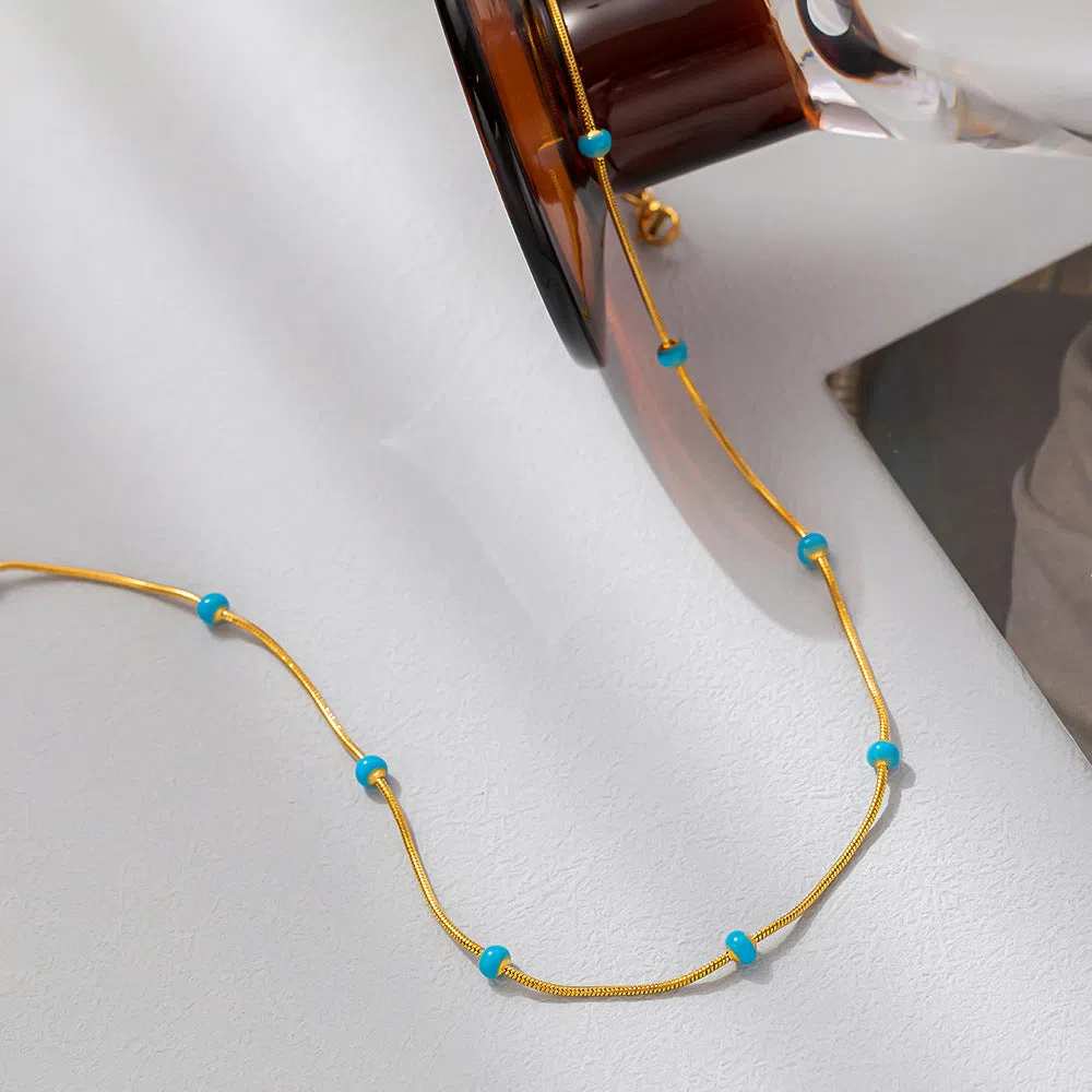 Titanium steel ball drop glaze necklace in green pearl gold, clavicle length, on model