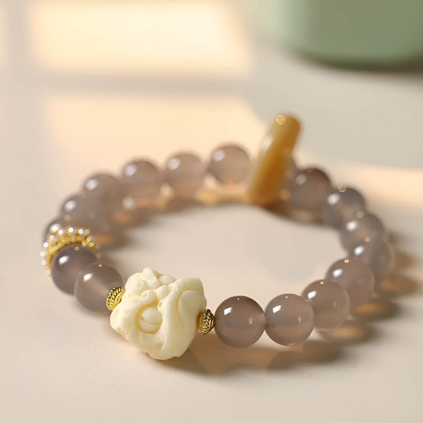 Hand-woven bracelet with large round grey agate and mellite beads on wrist.