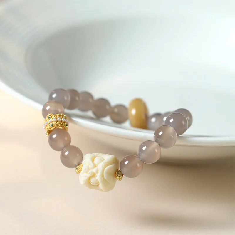 Hand-woven bracelet with large round grey agate and mellite beads on wrist.