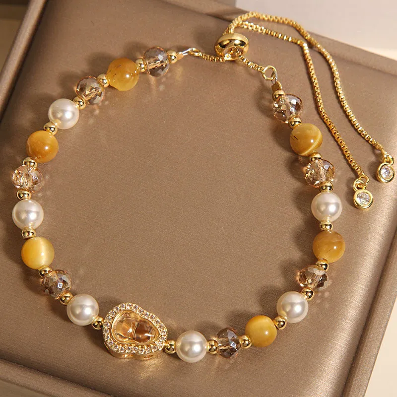 Yellow tiger's eye glass gourd pendant bracelet with alloy inlay and stone accents on a wrist.