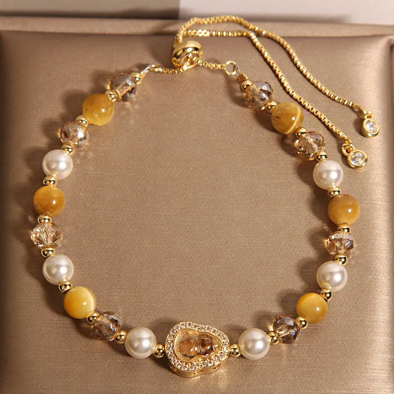 Yellow tiger's eye glass gourd pendant bracelet with alloy inlay and stone accents on a wrist.