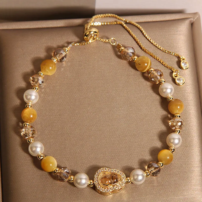 Yellow tiger's eye glass gourd pendant bracelet with alloy inlay and stone accents on a wrist.