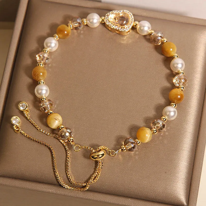 Yellow tiger's eye glass gourd pendant bracelet with alloy inlay and stone accents on a wrist.