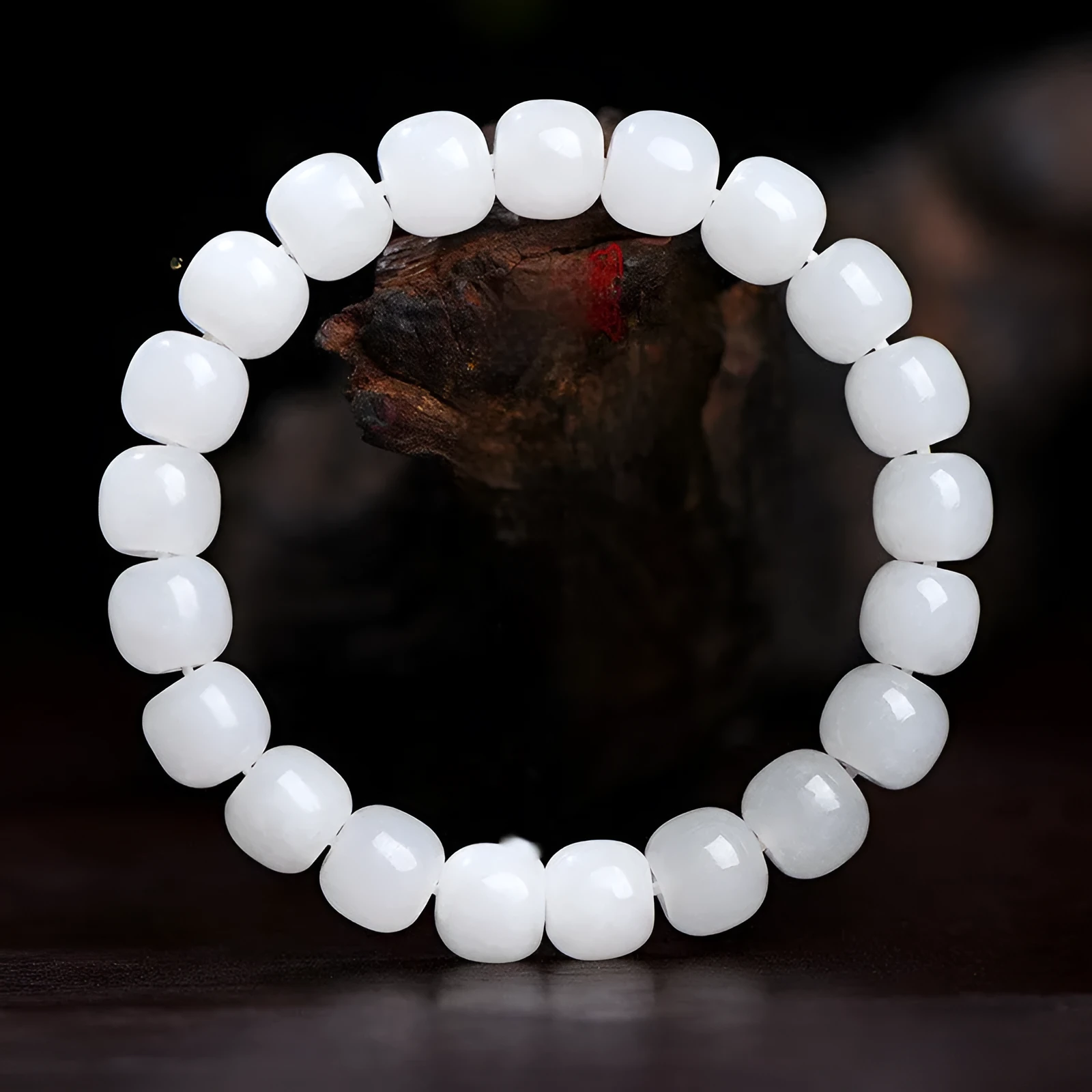 White Hetian jade barrel bead bracelet for men and women on a wooden surface.