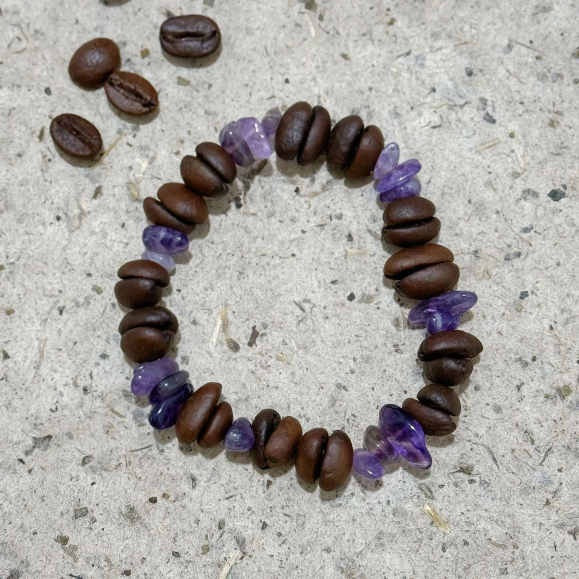 Handmade coffee bean bracelet with 16mm geometric charm showing colour variations